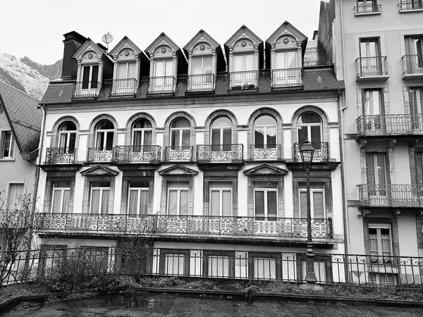 Immeuble à balcons du centre de Cauterets, sommets enneigés au fond (février 2024)