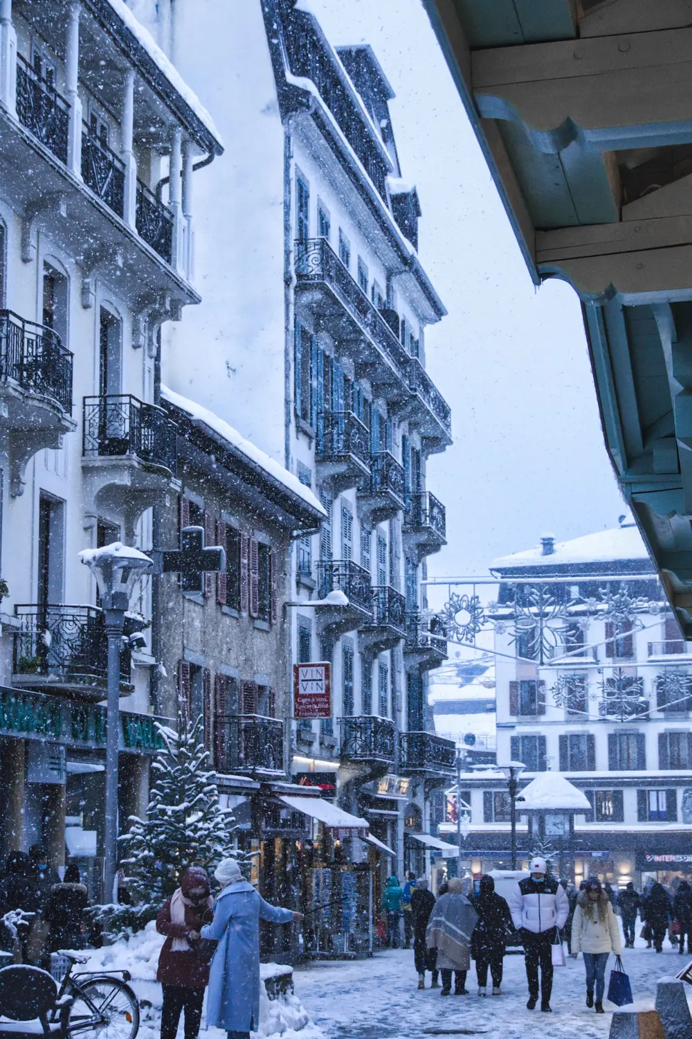 Rue du centre de Chamonix sous la neige, avec des passants et des décorations d'hiver