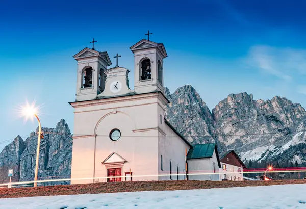 Une église de Cortina d'Ampezzo au crépuscule, au pied des Dolomites enneigées