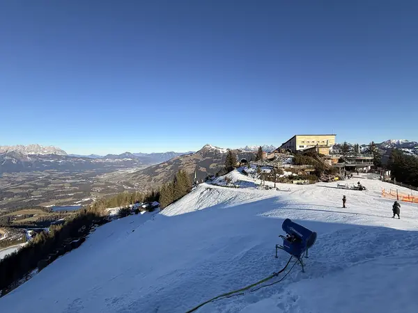 Sommet du Hahnenkamm : piste damée, enneigeur et vue sur la vallée de Kitzbühel, décembre 2025