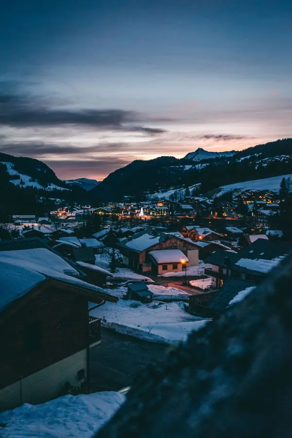 Le village des Gets sous la neige au crépuscule, montagnes au fond