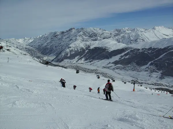 Skieurs sur une piste du secteur Blesaccia (Carosello 3000), vallée de Livigno en fond